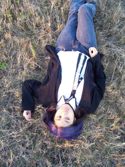1994 Ford Probe - A person rests in a field of dry grass, their purple hair contrasting with the muted tones of the landscape.
