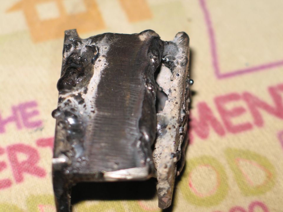 Close-up of a heavily welded metal component with rough edges and slag