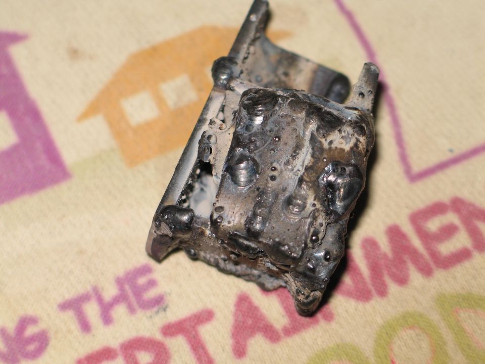 Small hand-welded steel bracket with heavy weld beads on printed cloth