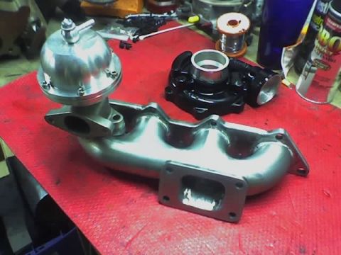 1999 Mitsubishi Mirage - Aftermarket turbocharger and wastegate assembly components are laid out on a red mat, suggesting a performance modification project.