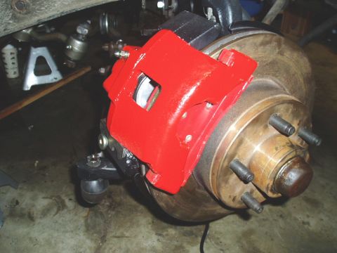 1966 Ford Fairlane - A red brake caliper is installed over a vehicle's rotor and wheel hub assembly.