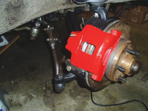 1966 Ford Fairlane - Close-up of a red painted car brake caliper and suspension components.