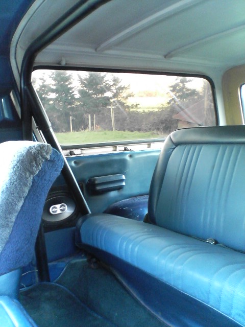 1978 Ford Bronco - Interior view of an SUV showing blue seats, a roll cage, and a glimpse of the outdoors.