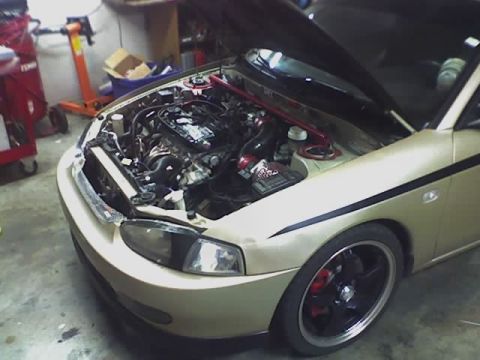 1999 Mitsubishi Mirage - The front 3/4 view of a gold 1999 Mitsubishi Mirage reveals its engine bay and custom modifications.