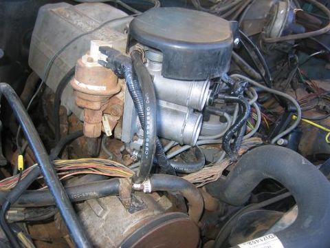 1986 Ford Bronco - Close-up of an engine bay, focusing on the carburetor and associated wiring and hoses.