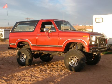 1984 Ford Bronco - This lifted red 1984 Ford Bronco is ready for adventure with its aggressive off-road tires and black top.