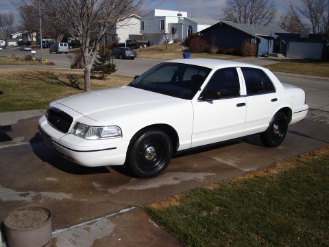 2000 Ford Crown Victoria - A white 2000 Ford Crown Victoria is parked on a driveway in a suburban neighborhood.