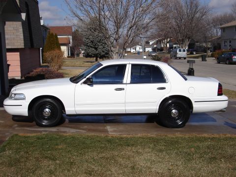 2000 Ford Crown Victoria - A white 2000 Ford Crown Victoria sedan is shown from the side, black steel wheels and tinted windows.