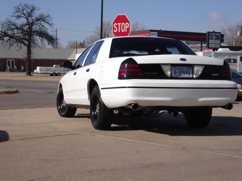 2000 Ford Crown Victoria - White 2000 Ford Crown Victoria parked outdoors, showing its rear end and exhaust pipes.