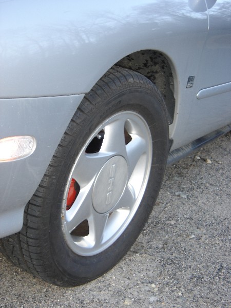 1999 Ford Taurus - Close-up of a silver car wheel, showing the tire and brake caliper.