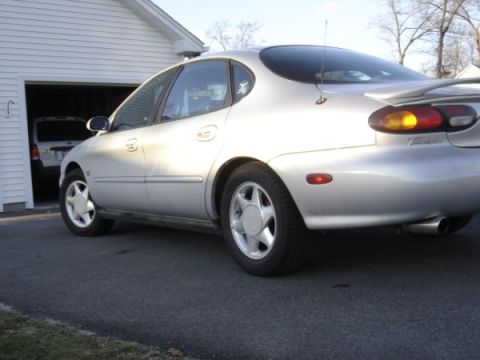 1999 Ford Taurus - Rear quarter view of a silver 1999 Ford Taurus parked in a driveway next to a garage.
