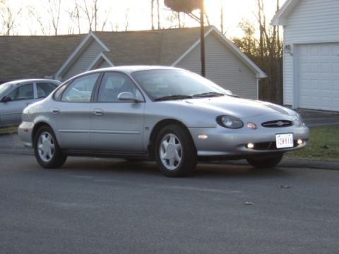 1999 Ford Taurus - A silver 1999 Ford Taurus is parked in front of a house and garage.