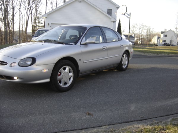 Silver sedan parked on asphalt, front 3/4 view. Red brake calipers visible