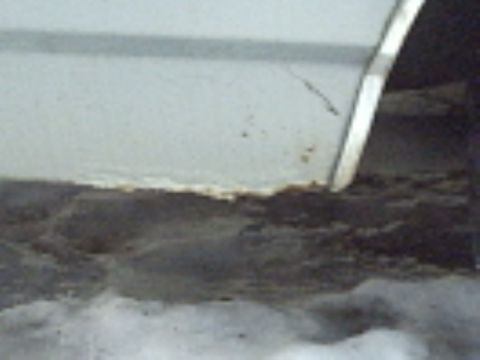 1991 Ford LTD Crown Victoria - The lower body panel of a vehicle shows significant rust and debris accumulation.