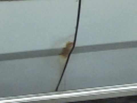 1991 Ford LTD Crown Victoria - A close-up view of a car door shows a small rust spot and a piece of black trim.