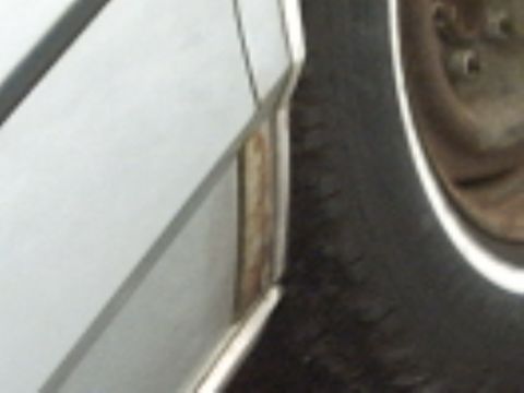 1991 Ford LTD Crown Victoria - Detail of a car's body panel and tire, showing a section of the vehicle.