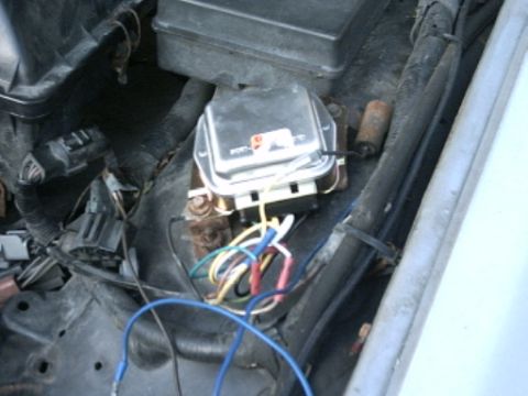 1991 Ford LTD Crown Victoria - A close-up view of a vehicle's voltage regulator and its wiring harness.
