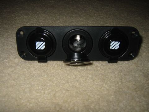 1992 Ford Bronco - A black panel with three power outlets, two of which have a striped logo, is shown against a carpeted surface.