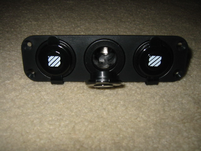 Black automotive power outlet panel with three circular sockets, two with white diagonal stripes