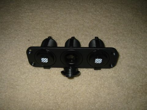 1992 Ford Bronco - This black switch panel features three circular openings, two with illuminated symbols and one central socket.