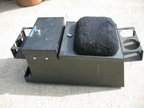1992 Ford Bronco - A black metal center console with cup holders and a fuzzy seat is shown on a concrete surface.