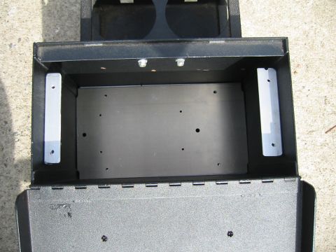 1992 Ford Bronco - Interior view of a black center console storage compartment with visible mounting hardware and openings.