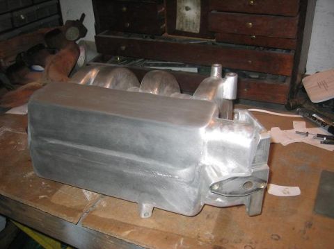 1986 Ford Bronco - An aluminum intake manifold sits on a workbench, ready for installation or modification.