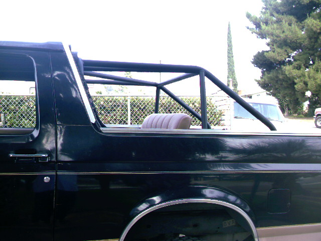 Black Ford Bronco side view with aftermarket roll cage and tan seat