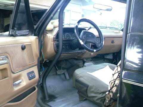 1989 Ford Bronco - The interior of a 1987 Ford Bronco shows a roll cage and aftermarket seat covers.