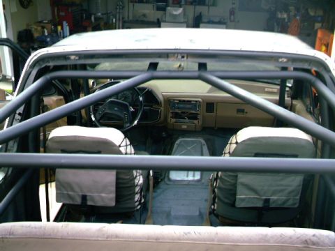 1989 Ford Bronco - The interior of a 1989 Ford Bronco is visible, a custom roll cage and tan upholstery.