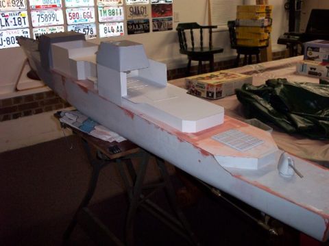 1998 Ford Crown Victoria - A model ship is displayed on a table, with a collection of license plates on the wall in the background.
