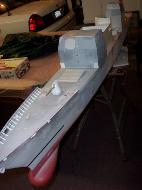 1998 Ford Crown Victoria - A model ship is displayed on a table, with a white car partially visible behind it.