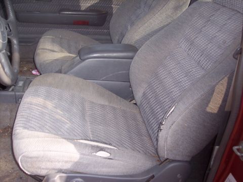 1995 Toyota Tacoma - The interior of this red truck shows significant wear on the fabric seats and center console.