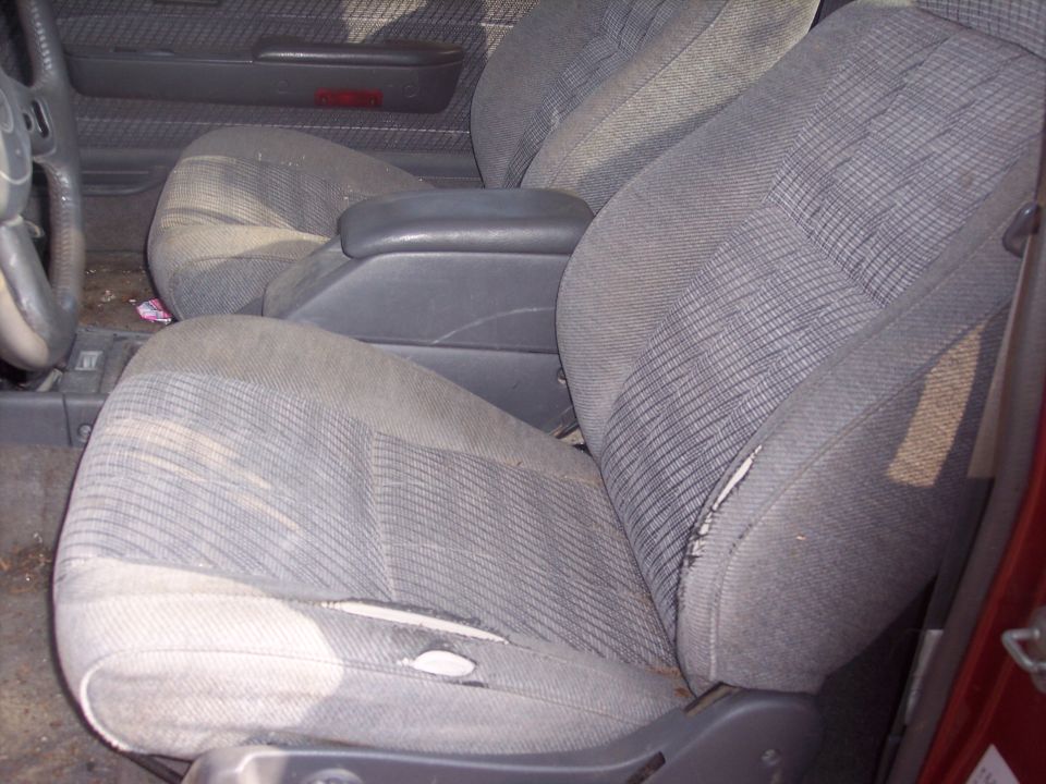 Interior view of worn fabric seats and center console in a red truck