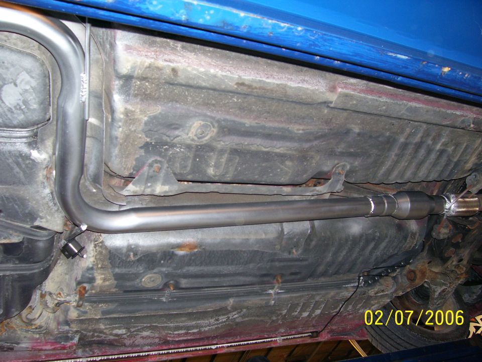Underside of a blue vehicle showing a new exhaust pipe and fuel tank. Date stamp reads 02/07/2006
