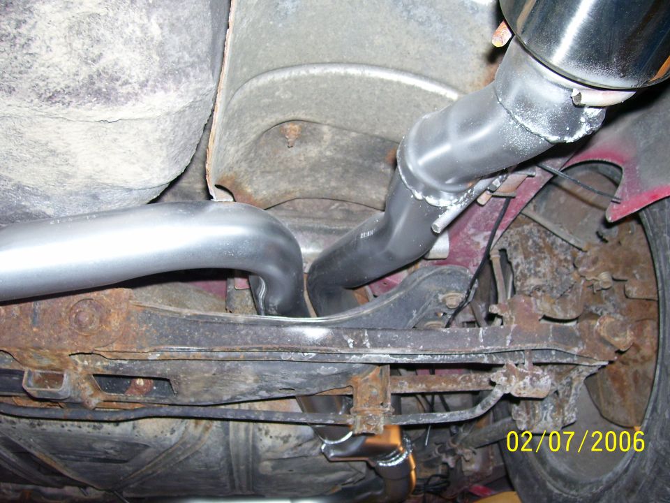Underbody view of custom dual exhaust piping routed over a rear axle with chrome tip