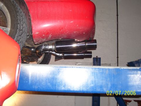 1994 Ford Probe - Dual exhaust pipes are visible on the underside of a red vehicle, possibly undergoing maintenance.