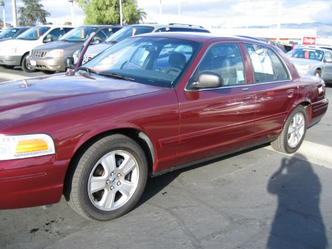 2005 Ford Crown Victoria - Side view of a red 2005 Ford Crown Victoria in a parking lot.