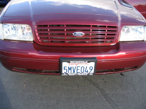 2005 Ford Crown Victoria - The grille and headlights of a red Ford Crown Victoria are visible, along with its license plate.