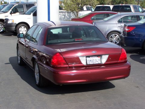 2005 Ford Crown Victoria - Rear view of a red 2005 Ford Crown Victoria, showing its distinctive taillights and license plate.
