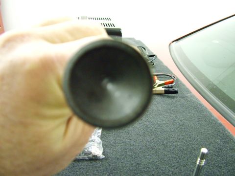 2003 Ford Mustang - A hand holds a metal object, obscuring the view of a car's interior and trunk interior.