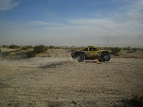 Yellow number 502 Beetle-bodied off-road buggy sliding through desert dust