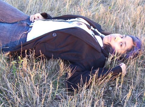 1994 Ford Probe - A young woman rests in a field of dry grass, her face turned towards the camera.