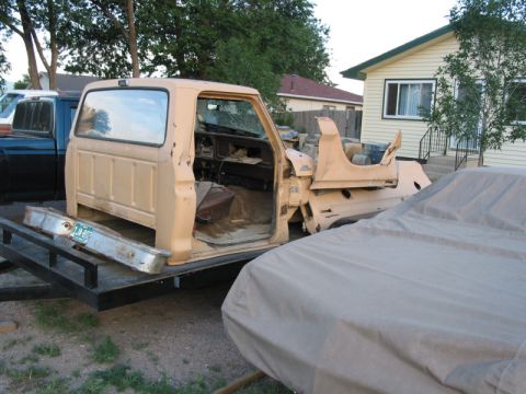 1981 Ford Bronco - A tan Ford Bronco body sits on a trailer, missing its doors and other parts.