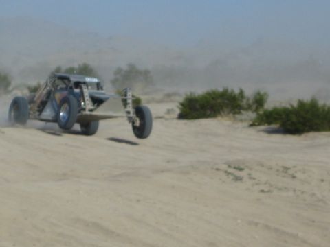 Off-road race buggy catching air over a sandy desert jump