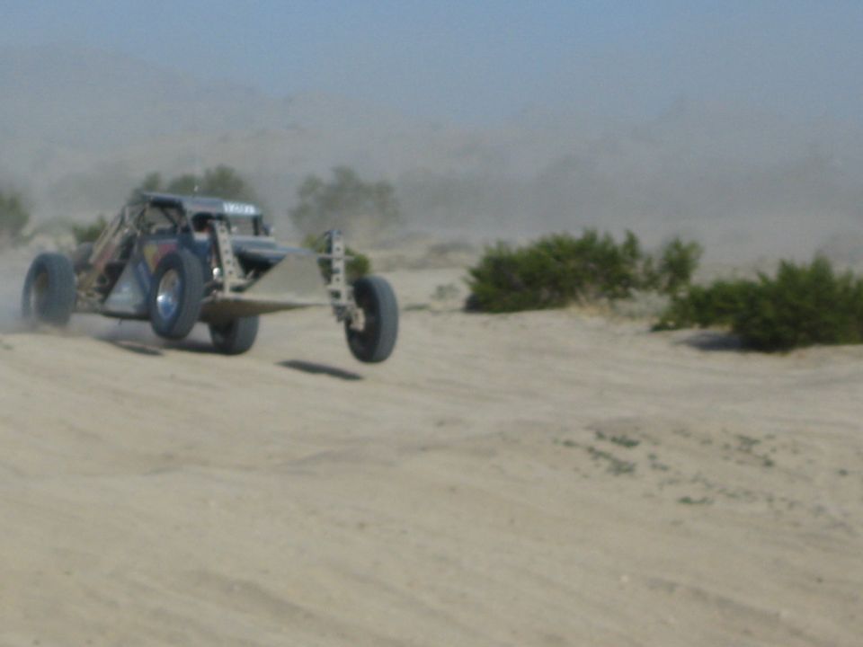 Off-road race buggy catching air over a sandy desert jump