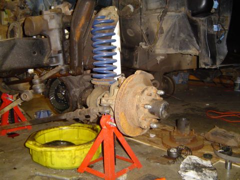 1979 Ford Bronco - Close-up of a vehicle's front axle and suspension components, undergoing maintenance or repair.