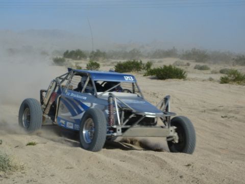 Blue and silver off-road race buggy number 123 sliding through desert sand