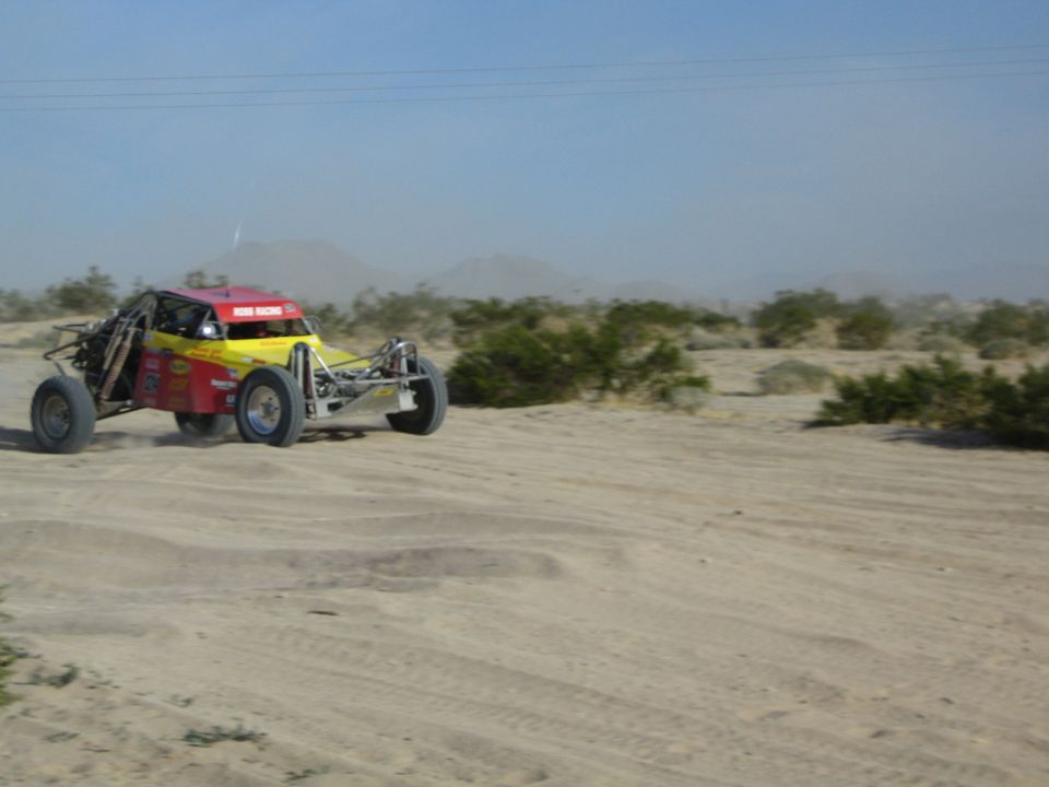 Red and yellow off-road race buggy speeding across flat desert sand