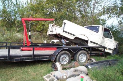 1988 Ford Bronco - A white pickup truck bed is being loaded onto a trailer with the assistance of a red engine hoist.